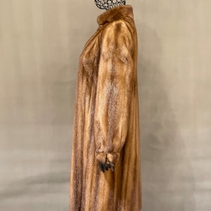 May include: A long brown fur coat with a high collar. The coat is made of a soft, luxurious fur and has a classic, elegant style.