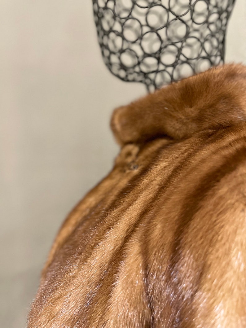 May include: A brown fur coat with a soft, luxurious texture. The fur is arranged in a striped pattern, creating a visually appealing design.