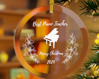 May include: A clear glass Christmas ornament with a white piano silhouette, floral accents, and the text "Best Piano Teacher Merry Christmas 2024".