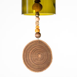 May include: A green glass bottle with a wooden disc hanging from it. The bottle has a wooden bead garland with brown, yellow, and orange beads.