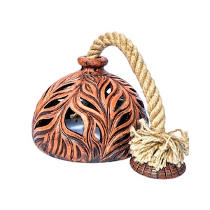 May include: A terracotta lampshade with a rope handle and a carved leaf design. The lampshade is brown with a reddish hue.