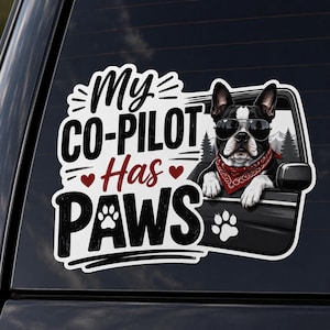 May include: A vinyl decal featuring a black and white French Bulldog wearing sunglasses and a red bandana, leaning out of a car window. The text reads My CO-PILOT Has PAWS, accompanied by red heart icons and paw print graphics on a white background.