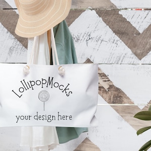 May include: White tote bag with the text "LollipopMocks" and "your design here" printed on it. The bag has rope handles and is sitting on a white and brown chevron patterned background.