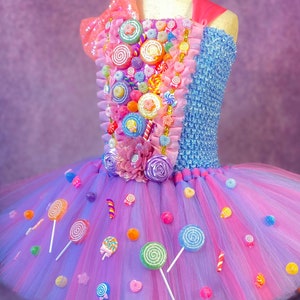 May include: A pink and blue tulle tutu dress decorated with colorful candy, lollipops, and bows. The bodice is blue with a pink and white candy design.