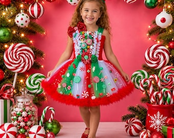 May include: A festive dress featuring a red and green tulle skirt adorned with various candy-themed embellishments, including lollipops and peppermint swirls. The bodice includes white ruffled trim, a large red bow, and a vibrant holiday color palette.