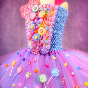 May include: A pink and purple tulle tutu dress decorated with colorful candy, lollipops, and sprinkles. The bodice is blue and features a variety of candy decorations.