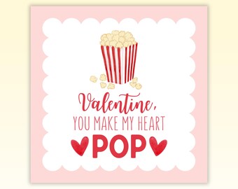 May include: A pink Valentine's Day card with a white scalloped border. The card features a cartoon illustration of a red and white striped popcorn bucket with popcorn inside. The text on the card reads "Valentine, you make my heart POP" with two red hearts.
