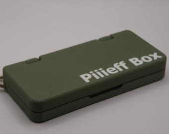 May include: A green pill box with a white string attached and the text "Pilieff Box" printed on the top.
