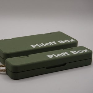 Pu&ograve; includere: Due scatole rettangolari verdi con un manico in corda. La scatola superiore ha il testo "Piliieff Box" stampato su di essa. La scatola inferiore ha il testo "Pieff Box" stampato su di essa.