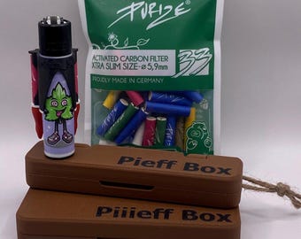 Può includere: Una scatola di legno marrone con il testo "Pieff Box" e "Piiieff Box" sulla parte superiore e inferiore della scatola. La scatola è aperta e contiene un accendino nero con un personaggio dei cartoni animati verde su di esso. Un sacchetto di filtri per sigarette verdi, blu e rossi è accanto alla scatola.