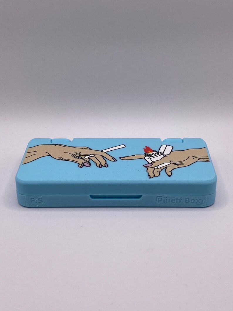 May include: A light blue Nintendo Switch game case with a graphic of two hands, one holding a cigarette and the other holding a lighter. The case has the text "Pilljeff Boxy" on the bottom right corner.