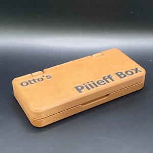 May include: A brown wooden box with the text "Otto's Pillieff Box" printed on the top.