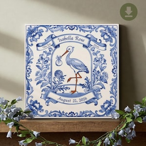 May include: Blue and white ceramic tile with a stork carrying a bundle, a banner with the name "Isabella Rose", the date "August 22, 2026", and the measurements "7lbs 2oz" and "30cm".