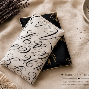 Peut inclure: Un pack de chaleur à deux faces. Un côté en coton crème avec des écritures noires, l'autre en soie noire avec des accents dorés. Le texte indique : « TWO SIDES - ONE HEAT PACK ». Idéal pour la thérapie par la chaleur.