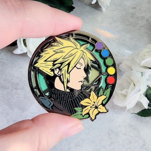 Könnte beinhalten: Eine runde, goldfarbene Emaille-Anstecknadel mit einem Charakter mit stacheligen blonden Haaren, einem schwarzen Hemd und einer gelben Blume. Der Charakter ist von einem grünen und schwarzen Glasmalereidesign mit einem Regenbogen aus farbigen Kreisen umgeben.