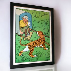 Könnte beinhalten: Eine gerahmte Illustration eines Comic-Charakters, ein junger Junge mit Safarihut, der in einem Durchgang sitzt, mit einem weißen Hund. Ein Leopard mit geflecktem Fell steht im Gras vor dem Durchgang und schaut den Jungen an.