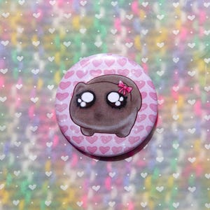 May include: A brown cartoon animal with big eyes and a pink bow on its head. The animal is surrounded by pink hearts on a white background.