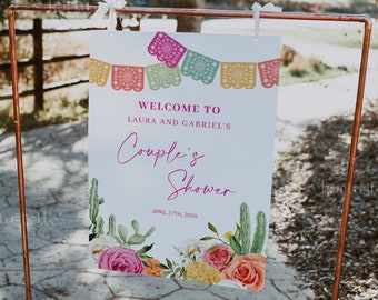 Peut inclure: Une pancarte blanche avec un motif floral rose et vert et le texte "Bienvenue à Laura et Gabriel's Couple's Shower April 27th, 20XX". La pancarte est suspendue à un support en cuivre.