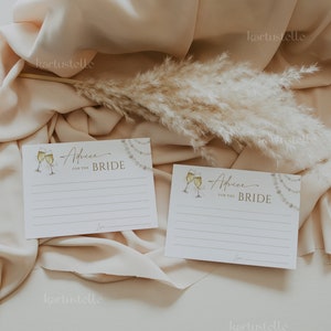 May include: Two white cards with gold lettering and illustrations of champagne glasses. The cards have lines for writing advice for the bride. The text on the cards reads "Advice for the Bride".