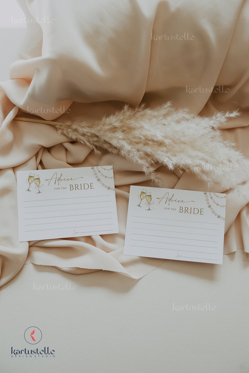 May include: Two white cards with gold lettering and illustrations of champagne glasses. The cards have lines for writing advice for the bride. The text on the cards reads "Advice for the Bride".