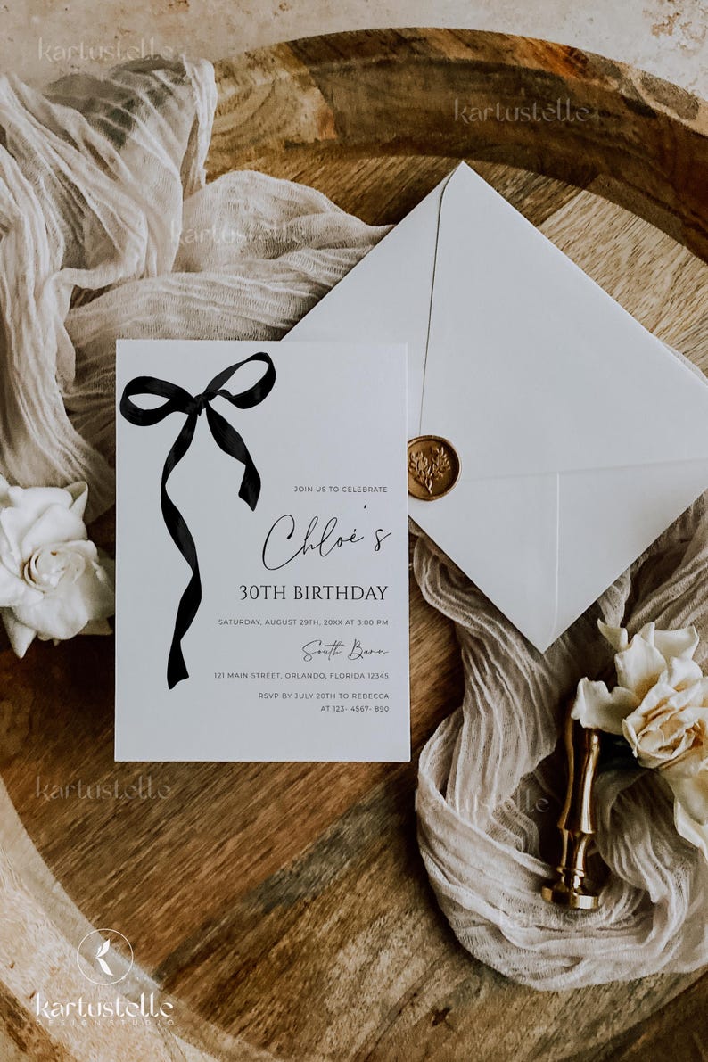 K&ouml;nnte beinhalten: Eine wei&szlig;e Einladungskarte mit schwarzem Schleifendesign und dem Text "Chloe's 30th Birthday". Ein Umschlag mit goldenem Siegel und ein Holztablett mit Stoff und Blumen vervollst&auml;ndigen das elegante Design.