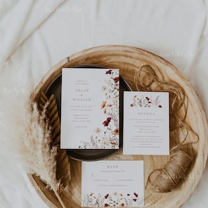 May include: Wedding invitation suite with floral designs in shades of burgundy, white, and green. The invitation card features the names "Chloe & William" and the date "October 27th, 20xx". The details card includes information about the ceremony and reception. The RSVP card has a section for guests to indicate their attendance and dietary requirements.