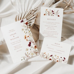 May include: Wedding invitation suite with a floral design featuring burgundy, orange, and white flowers. The invitation includes the names Chloe & William, the date October 17th, 2023, and the time 4 o'clock in the afternoon. The details card includes the venue, Woodland West Barn, 3010 Main Street, Atlanta, Georgia 30311. The RSVP card includes a space for guests to indicate their attendance and dietary requirements.