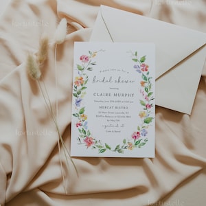 Puede incluir: Una invitaci&oacute;n de ducha nupcial floral con una corona de acuarela de flores rosas, amarillas y moradas. La invitaci&oacute;n es para Claire Murphy e incluye la fecha, la hora y el lugar de la ducha. Tambi&eacute;n indica que la invitada de honor est&aacute; registrada en Crate & Barrel.