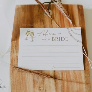 May include: White card with gold text that reads "Advice for the Bride". The card has a watercolor illustration of two champagne flutes and a pearl necklace.