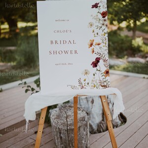 Może przedstawiać: Biały znak z kwiatowym wzorem i tekstem "Witamy na Bridal Shower Chloe 26 kwietnia 20xx" wyświetlonym na sztaludze.