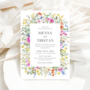 May include: A wedding invitation with a floral border featuring colorful wildflowers in shades of pink, yellow, orange, and blue. The invitation includes the names Sienna and Tristan, along with the wedding date, time, and location.