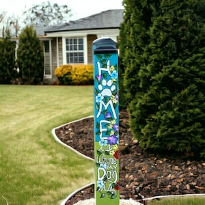 May include: A colorful wooden sign with the words "Home is where my dog is" painted on it. The sign is decorated with flowers and paw prints.