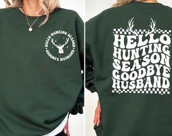 May include: Dark green sweatshirt with white text and a deer graphic. The front reads "Hello Hunting Season Goodbye Husband" in a circular design. The back features the same text in a square design with antlers.