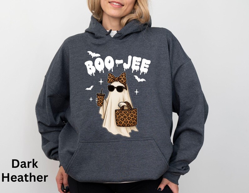 Op de afbeelding: Donkergrijze hoodie met een Halloween-thema. De afbeelding toont een spook met een zonnebril en een luipaardprint strik, met een koffiebeker en een handtas. Het woord "BOO-JEE" staat boven het spook.