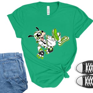 Peut inclure: Un t-shirt vert avec un personnage de dessin anim&eacute; v&ecirc;tu de blanc et de vert. L'image montre &eacute;galement un jean bleu et des baskets noires en toile avec des semelles et des lacets blancs. Le t-shirt est nou&eacute; &agrave; la taille.