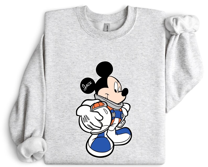 Peut inclure: Sweat-shirt gris clair avec un personnage de dessin anim&eacute; Mickey Mouse dans un design de combinaison spatiale. Le personnage porte une combinaison spatiale bleue et orange avec des gants et des bottes blancs. Le nom "Jack" est &eacute;crit sur l'oreille.