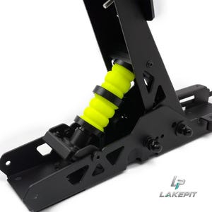 Peut inclure: Un ensemble de pédales de course en métal noir doté d'un amortisseur cylindrique en caoutchouc jaune néon vif. La structure comprend un bras de pédale vertical avec des découpes triangulaires et un cadre de base. Le logo LAKEPIT est visible en bas à droite.