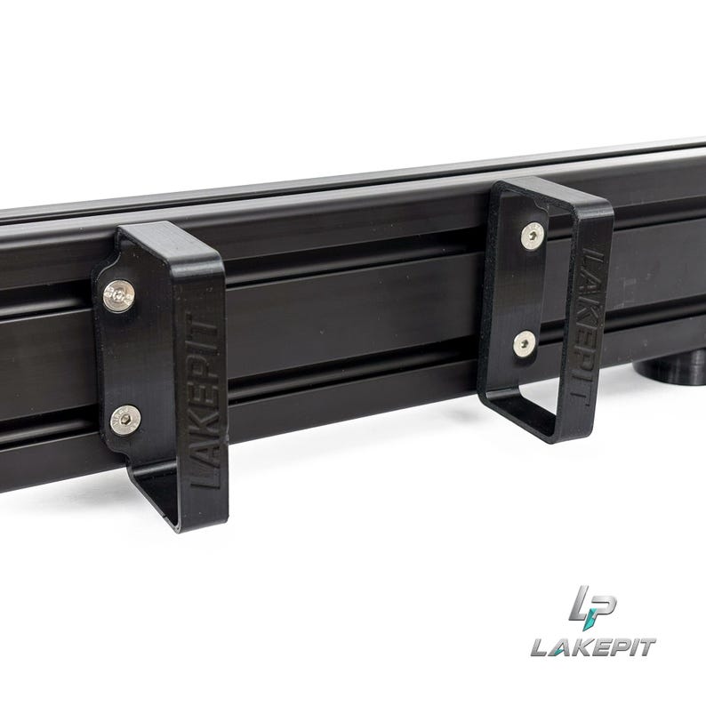 May include: A black aluminum extrusion rail featuring two attached black plastic brackets. Each bracket is secured with two silver metal screws and features the embossed text LAKEPIT on the side. The overall structure is matte black.