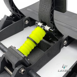 以下が含まれることがあります： 鮮やかなネオンイエローの円筒形ゴム製ダンパーを備えた黒いレーシングペダルアセンブリ。メカニズムには、質感のある黒いプラスチックフレーム、金属製のボルト、白いプラスチック製のスペーサーが含まれています。隅にLAKEPITのロゴが表示されています。
