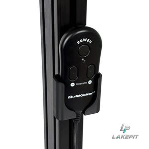 May include: A black ButtKicker remote control with a power button and intensity adjustment buttons is mounted in a black plastic holder attached to a vertical black aluminium extrusion rail. A black power cord extends from the bottom of the remote.