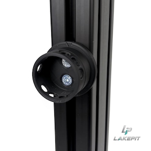 May include: A black 3D-printed circular cup holder mount attached to a vertical black aluminium extrusion profile. The mount features two silver metal bolts securing it to the frame, with small circular cutouts along the rim of the holder.