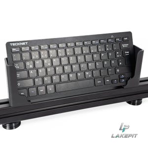 Op de afbeelding: Een zwart TeckNet draadloos toetsenbord met een QWERTZ-indeling wordt vastgehouden in een zwarte plastic standaard. Het toetsenbord heeft witte letters op de toetsen, inclusief functietoetsen, een backspace-toets en een enter-toets. LakePit-logo.