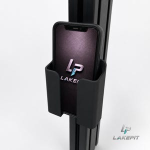 Könnte beinhalten: Eine mattschwarze Smartphone-Halterung, die an einem vertikalen schwarzen Aluminium-Strangpressprofil befestigt ist. Die Halterung enthält ein Smartphone mit dunklem Bildschirm und dem weiß-blauen Logo-Schriftzug "LP LAKEPI" in der Mitte.