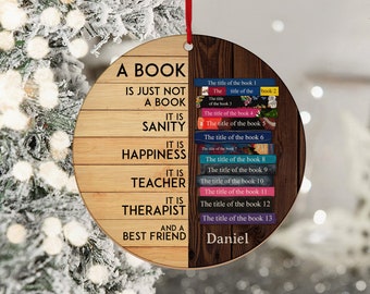May include: A round wooden ornament with a quote about books. The quote reads "A book is just not a book. It is sanity. It is happiness. It is teacher. It is therapist. And a best friend." The other side of the ornament has a list of book titles with the name "Daniel" at the bottom.