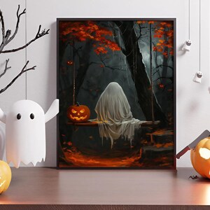 May include: A framed Halloween-themed artwork depicts a ghost on a swing in a dark forest with a carved pumpkin. Decorative hanging ghosts and pumpkins are on a wooden surface, with a white ghost-shaped light and a black tree branch.