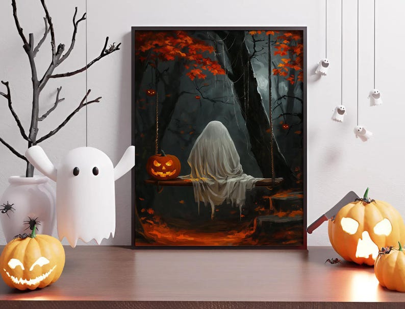 May include: A framed Halloween-themed artwork depicts a ghost on a swing in a dark forest with a carved pumpkin. Decorative hanging ghosts and pumpkins are on a wooden surface, with a white ghost-shaped light and a black tree branch.