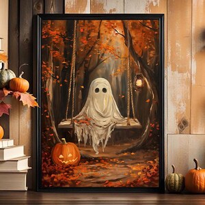 May include: A framed Halloween-themed painting depicts a ghost on a swing in a forest with autumn leaves. A carved pumpkin sits in front of the painting. Pumpkins and fall foliage are arranged around the painting, creating a seasonal display.