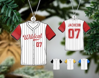 May include: White and red baseball jersey ornament with the text "Wildcat 07" on the front and "JACKOB 07" on the back. The ornament is hanging from a silver chain.