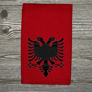 May include: A red kitchen towel with a black double-headed eagle design. The eagle is the national symbol of Albania.