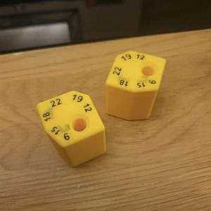 Könnte beinhalten: Zwei gelbe sechseckige Messwerkzeuge mit den Zahlen 6, 12, 15, 18, 19 und 22, die auf den Seiten aufgedruckt sind.